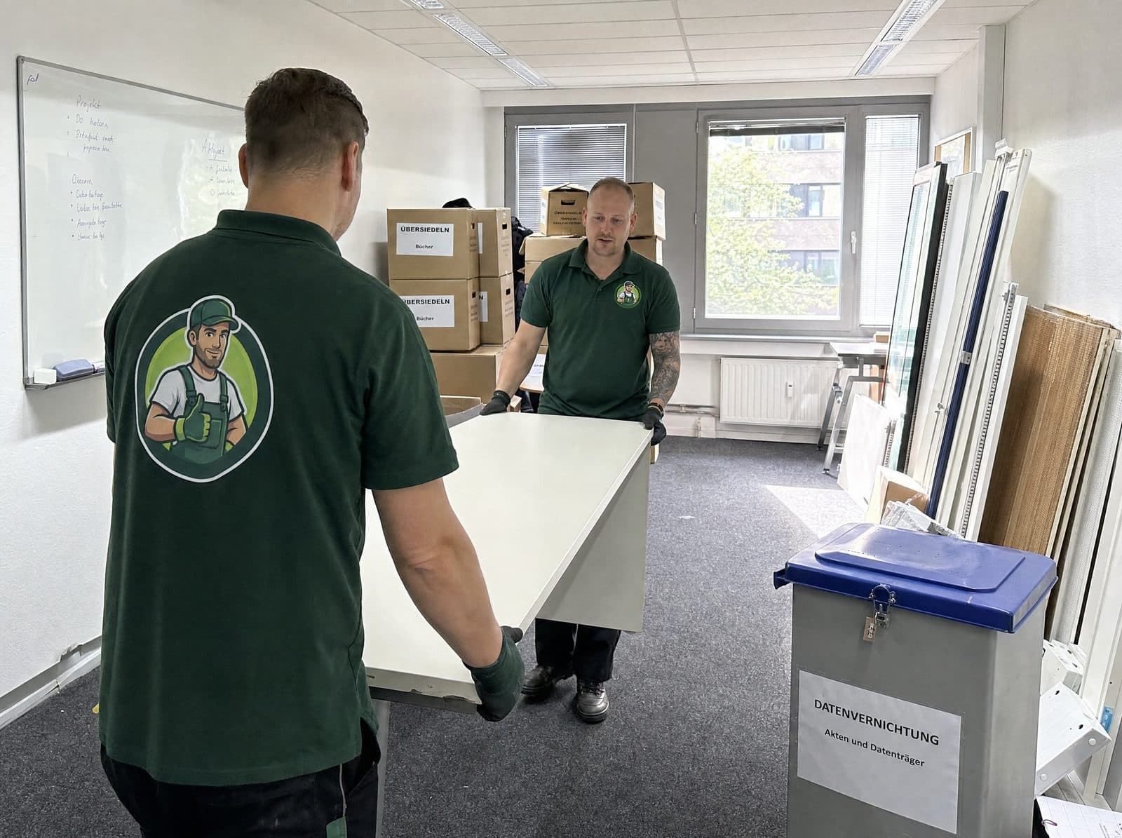 Team räumt ein Büro und trägt Schreibtische und Aktenkartons bei einer Firmenauflösung