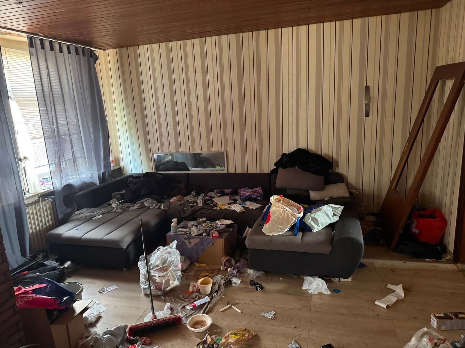 Vermülltes Wohnzimmer mit Sofa in einer Wohnung in Duisburg vor der Räumung